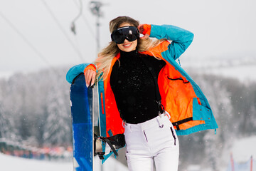 Happy girl snowboarder posing in sunglasses with snowboard
