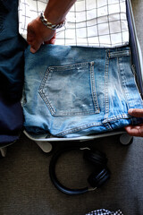 Fototapeta na wymiar Hands of unrecognisable man packing his casual jeans, shirts in suitcase for travel