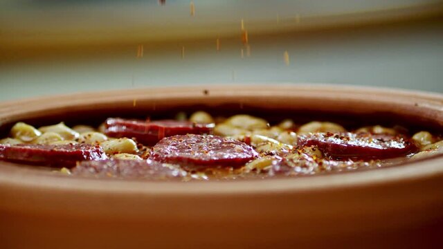 In slow motion, seasoning is poured over the sausage (Turkish sucuk) and beans. Slow motion Turkish food( Kuru Fasulye) 	