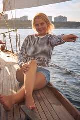 Happy woman sits on the deck of a yacht in the black sea at sunset. View from above