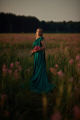 Fototapeta premium Young beautiful girl with a bouquet of flowers in her hands at sunset.