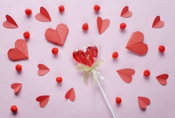 Valentine's day flat lay photography with red heart shape lollipop and paper cut hearts. Romantic greeting card background. 