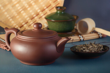 Chinese clay teapot, traditional porcelain teacup and tea ceremony items on blue table
