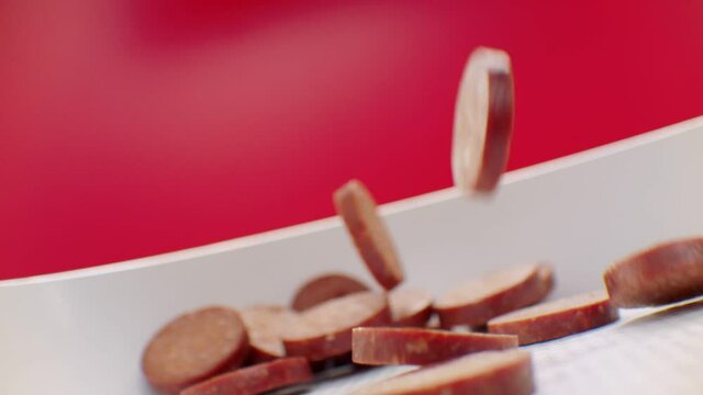 Sliced Turkish sausages (sucuk) fall into the pan in slow motion. Turkish sausages (sucuk)