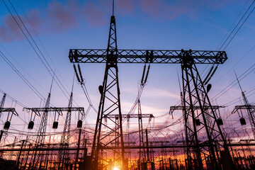 A silhouette of high voltage power lines against a colorful sky at sunrise.
