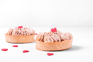 Mini Banoffee pie topped with sugar heart on the white table. Dessert with banana, toffee and whipped cream for Valentines Day