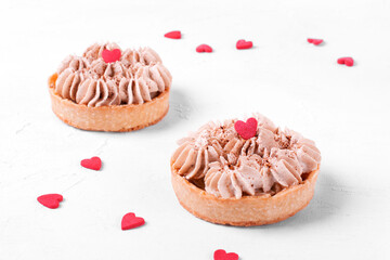 Mini Banoffee pie topped with sugar heart on the white table. Dessert with banana, toffee and whipped cream for Valentines Day