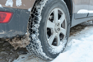 Parts of the car are covered with snow and ice after a snowfall. Wheel close-up in dirt and anti-icing reagents. Big frosts and a lot of snow in the city. Problems on winter slippery roads.