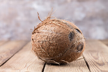 A large coconut lies on a wooden table against a light, blurry background. Healthy food.