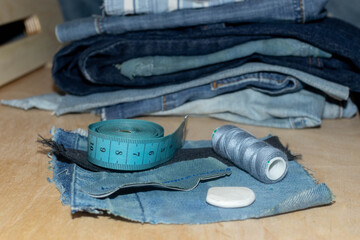 New things from old jeans: denim ready to upcycling and tailoring accessories: thread, tape measure, a piece of chalk. Concept of things reuse and natural resources preserving.