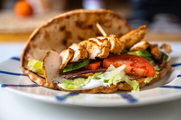 Chicken shawarma in pita bread with vegetable salad on plate on table.
