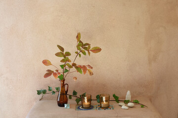 Small altar with natural tree, stones, quartz and candles on a natural pink textured wall.