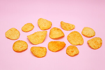 Potato chips are laid out on a pink background. Modern style. The view from the top.