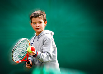 Little boy tennis player on a blurred and zooming green background