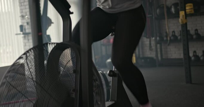 Muscular sportswoman breathing heavily and exercising on stepping machine during intense fitness training in gym