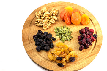 On a wooden kitchen board, an assortment of healthy tasty dried fruits and nuts for a healthy diet.