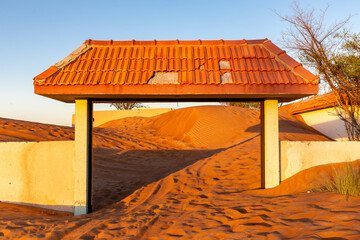 Wall and tiled gate buried in sand dunes in the desert in Al Madam ghost village, United Arab...