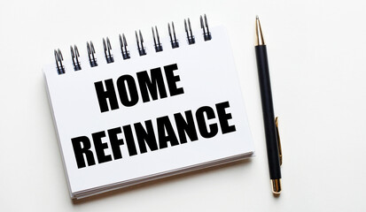 On a light background, a white notebook with the words HOME REFINANCE and a pen.