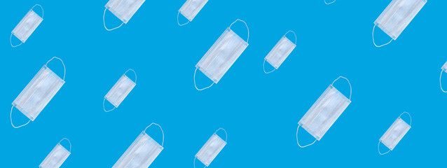 Many medical masks on a blue background cover the mouth and nose to protect against viruses and bacteria. Epidemic concept. Regular pattern, flat lay.