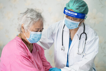 Doctor checking Asian senior or elderly old lady woman patient wearing a face mask in hospital for protect infection Covid-19 Coronavirus.