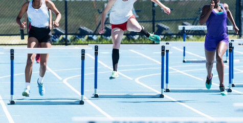 Three female hurdler runners in outdoor track race