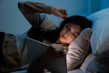 Caucasian women are using the tablet computer on the bed before she sleeping at night, Mobile addict concept, Blue light harmful to the eyes.
