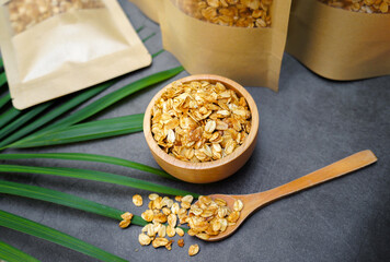 Homemade granola in a wooden bowl and in a paper bag placed on the table.