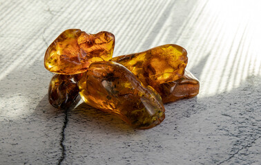 Sparkling old orange Baltic amber stones   beautifully stacked one on top of the other on a gray background. Material for jewelers, amber texture.