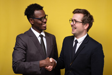 Handshake of two business people. Two men making a deal. Studio shot on yellow wall.