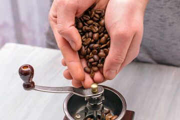 man grinds coffee beans in a manual coffee grinder hands fall asleep grain in the coffee grinder
