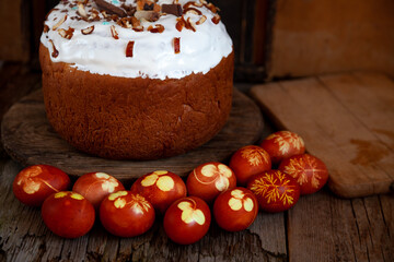 Easter cake and colored eggs. Rustic food on a wooden table. Egg colored with onion peel. Clover and dill leaves pattern. Classic food for the Easter holiday