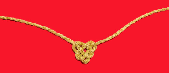 Sisal string, rope bonding on red Background, in heart shape knot isolated on red table background. Love symbol. Love, Valentine's Day Concept. Flat lay. Panoramic web banner background