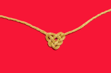 Sisal rope bonding on red Background, in heart shape knot on red table background. Love symbol. Love, Valentine's Day Concept. Flat lay