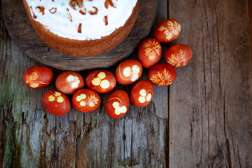 Easter cake and colored eggs. Rustic food on a wooden table. Egg colored with onion peel. Clover and dill leaves pattern. Classic food for the Easter holiday