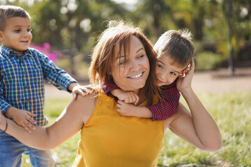 Latin woman smiling while having a playful time with twin sons in nature outdoor - Mother and...