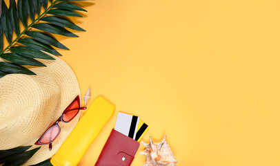 Vacation travel accessories, glasses, sunscreen, hat, wallet, credit cards on a bright yellow...