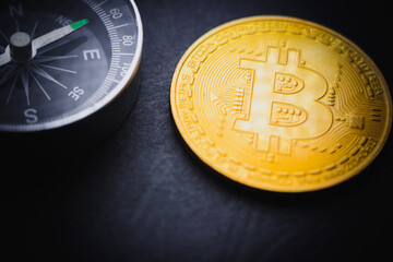 gold color bitcoin coin and compass on dark background close up