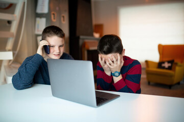 boy covering his eyes while looking at a laptop