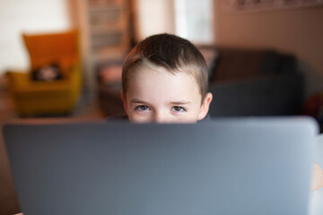 boy's eyes looking over the top of a laptop 
