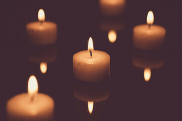 Fototapeta na wymiar Candles burning in the dark (low-key image)