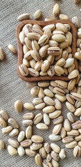 fried pistachios lie in a wooden menagerie scattered around on a wooden table and burlap