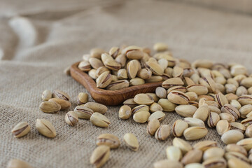 fried pistachios lie in a wooden menagerie scattered around on a wooden table and burlap