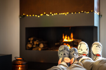 Couple sitting in front of the fireplace relaxes with the warm fire by warming their feet. Concept of winter holidays, christmas holidays and love on valentines day
