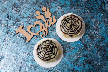 Two cakes with almond chips, chocolate, icing and cream on a blue background, for lovers on the holiday of February 14