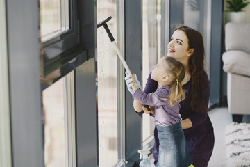 Woman and her little daughter cleaning window. Family at home.