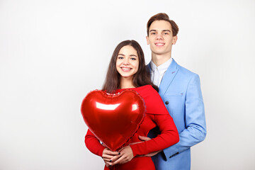 Fototapeta na wymiar Happy Valentine's day concept. Studio shot of couple in love holding a heart shaped balloon, showing affection. 14th february - the lovers day. White background, copy space, front view portrait.