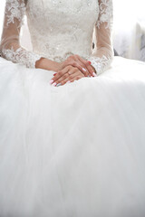 the bride folded her hands with a beautiful manicure on the wedding dress