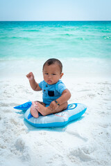 A small child on the white sand beach in front of the blue water