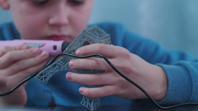 a boy makes a 3 d model with a pen. assembling the layout of the Elfin tower. young architect at work.