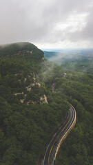Winding road through green hills with low clouds